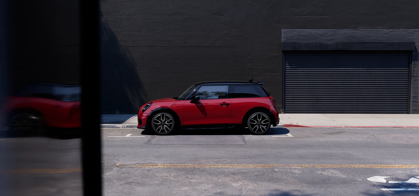 Vue latérale de la MINI Cooper en Chili Red et à toit noir en stationnement.