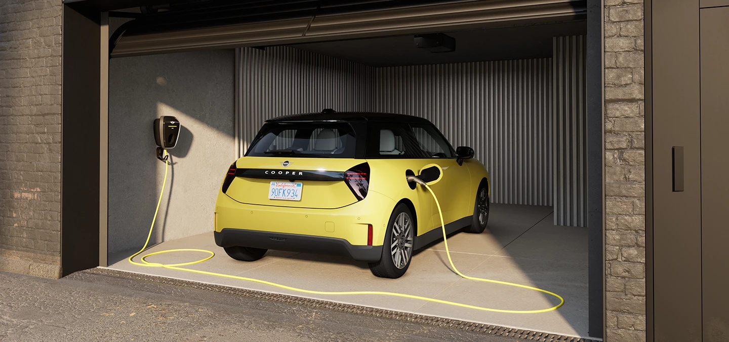 Vue arrière d'une MINI Cooper Electric Sunnyside Yellow en cours de recharge dans un garage. 
