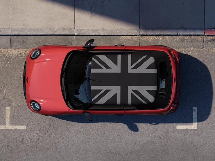 Vue du dessus de la MINI Cooper Cabrio Chili Red avec toit MINI Yours stationnée en ville.